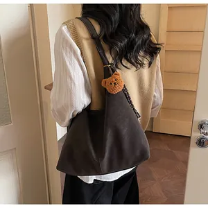 Donkerbruine shopper van mat leer met pluche beer hanger gedragen over de schouder