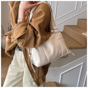 Detail of cream shoulder bag featuring embossed texture and reinforced wide strap design