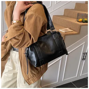 Detailed view of the black glossy pillow bag with silver metal rings and wide shoulder strap