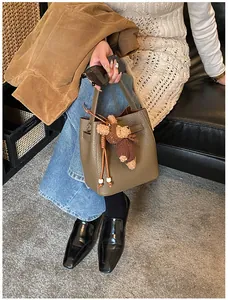 Detail of olive bucket bag with textured leather, silver hardware and a cute bear charm