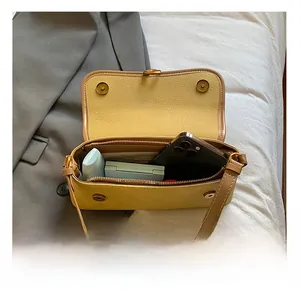 Détail intérieur du sac en cuir litchi jaune montrant la poche zippée et sa grande capacité