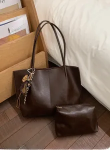 Detail of dark brown leather tote bag set with heart leopard charm and inner pouch