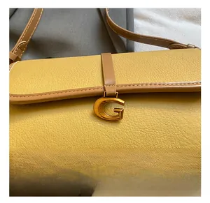 Détail du cuir grainé jaune et de la boucle métallique dorée en G sur le sac à main