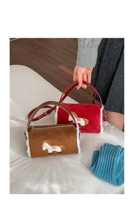 Detail of suede baguette bag featuring soft faux shearling trim and embroidery