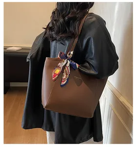 Détail du sac cabas en cuir marron avec anse en foulard de soie et lettrage doré