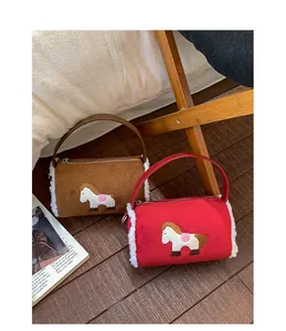 Miniature cylindrical velvet bags with plush trim and horse embroidery on wood floor