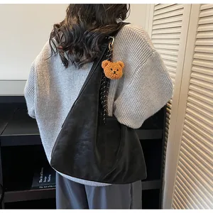 Gedetailleerd beeld van zwarte leren draagtas met berenhanger en twill zijden sjaal