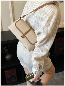 Détail du sac en cuir blanc cassé avec bordure marron et boucle G en bronze vintage