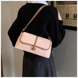 Détail du sac baguette en cuir grainé rose avec boucle G dorée porté par un modèle