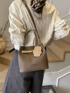 Brown textured leather bucket bag with gold clasp and adjustable shoulder strap