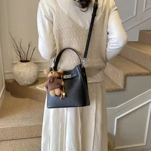 Minimalist black pebble leather bucket bag with silver lock and bear charm accessory