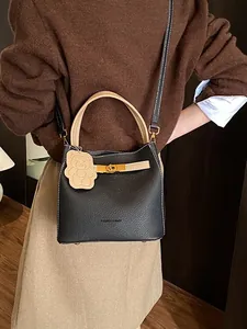 Litchi pattern bucket bag in black and beige with a bear charm and gold metal lock