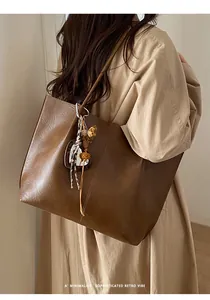 Detail view of brown vintage leather tote with leopard ribbon and chic heart charm pendant