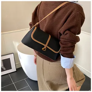 Détail du sac baguette en cuir noir avec bandoulière marron et boucle dorée en forme de G