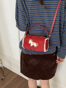 Red cylindrical faux suede crossbody bag with horse embroidery and white fleece trim