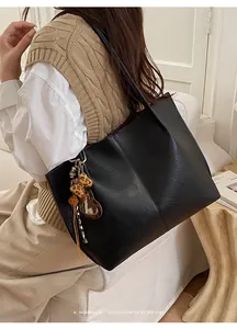 Detailed view of black retro tote bag with leopard heart charm and leather texture