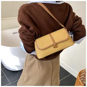 Détail du sac baguette jaune moutarde avec bordure en cuir et boucle métallique en C