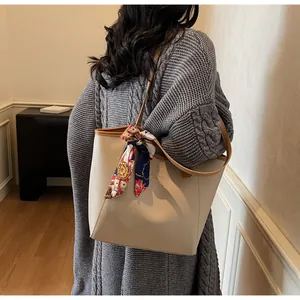 Détail d'un sac cabas en cuir beige avec un foulard floral décoratif sur la bandoulière