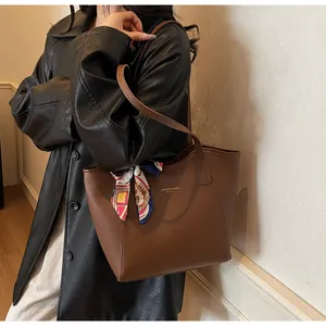Détail d'un sac cabas en cuir marron foncé avec un foulard en soie floral sur la lanière