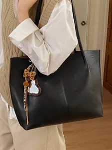 Minimalist black faux leather tote bag with stylish leopard print plush bow charm