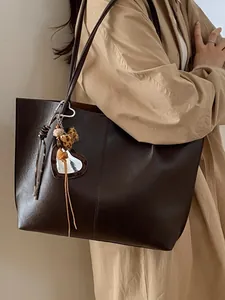 Chic coffee brown large tote bag with leopard bow pendant shown on a trench coat model