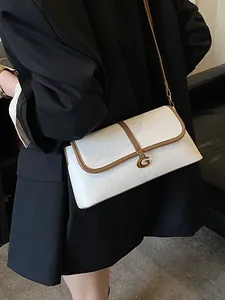 Sac baguette chic en cuir blanc avec bordure marron et fermoir G doré sur modèle