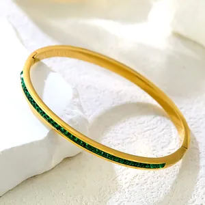 Luxurious gold titanium bracelet featuring square-cut green zircons on a stone background