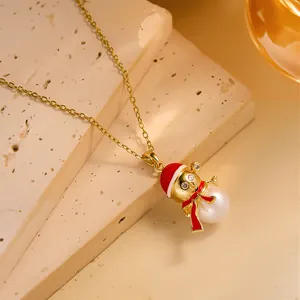 Detail view of a gold Christmas tree pendant necklace with red enamel and white pearl