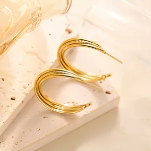 Detailansicht goldener geometrischer Ohrstecker mit Mesh-Textur auf Naturstein