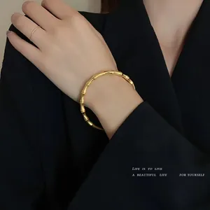 Dettaglio del braccialetto in oro 18k a forma di bambù sul polso di una modella