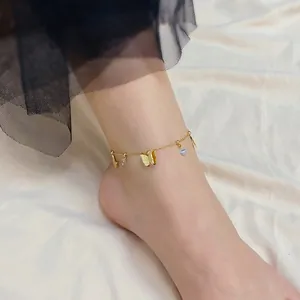 Close-up of a 18k gold butterfly anklet with sparkling zircons on a silk background
