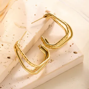 Detailansicht der goldenen geometrischen Ohrringe mit gedrehtem Seil und glatter Oberfläche