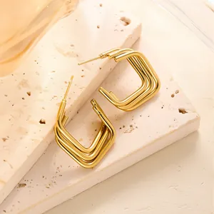 Nahaufnahme der goldenen geometrischen dreilagigen Rechteck-Ohrringe auf einem Stein