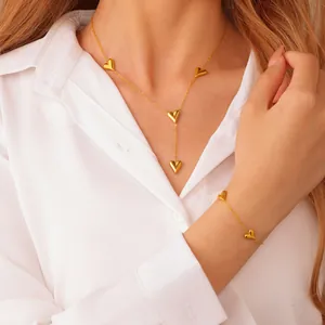 Elegant gold heart pendant necklace and bracelet set displayed on a white shirt