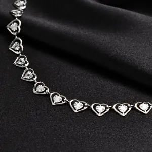 Silver hollow heart-shaped chain necklace with radial textured links on black satin