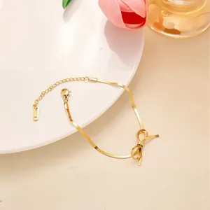 Dettaglio del bracciale a maglia serpente dorata con fiocco e chiusura a moschettone