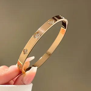 Detailopname van gouden klaverarmband met diamanten en geborstelde metaaltextuur