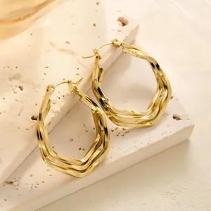 Makroaufnahme der mehrreihigen geometrischen Creolen aus 18K Gold auf strukturiertem Stein