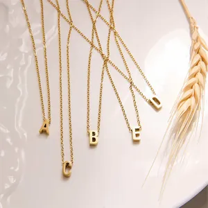 Detailansicht von 18k Gold-Anhängern A bis E an feinen O-Ketten auf einem weißen Keramiktablett