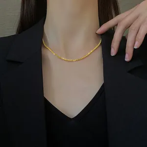 Gros plan d'un collier scintillant en acier titane plaqué or 18k porté par un mannequin