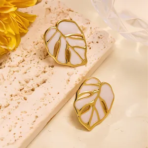 Vue détaillée des puces d'oreilles feuille de monstera dorées et émail rose pâle
