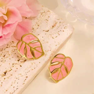 Gros plan de boucles d'oreilles feuille monstera rose avec bordure dorée élégante