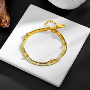 Details eines goldenen zweilagigen Schlangen- und Perlenarmbands mit Karabinerverschluss