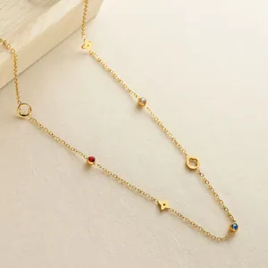 Elegante goldene Kleeblatt-Halskette mit hohlen Anhängern und bunten Kristallen auf Stoff