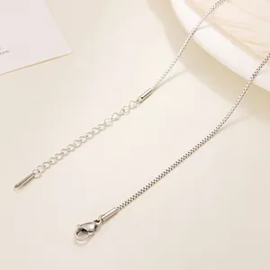 Detail of silver box chain necklace featuring a lobster clasp and adjustable link chain