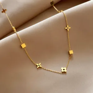 Detailed view of luxury gold clover and cube pendants on a satin background