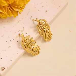 Detailed close-up of golden hollow leaf earrings on a textured stone surface