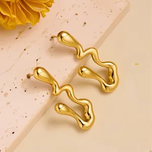 Detailed close-up of golden wavy earrings with a liquid metal texture on stone surface