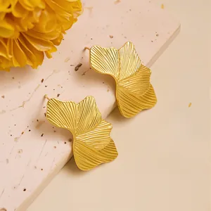 Macro detail of gold leaf stud earrings with linear texture and elegant petal design