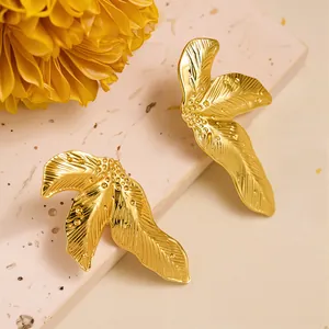 Macro detail of golden leaf-shaped titanium steel earrings with fine vein textures
